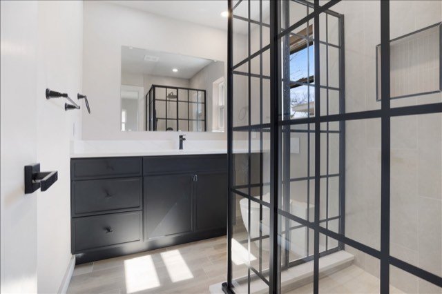 Bathroom with black framed glass shower and dark vanity